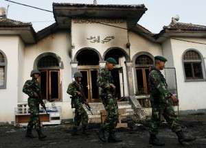 Soldiers walk past a burnt mosque belonging to an Ahmadiyah follower in Ciampea village of Indonesia's West Java province